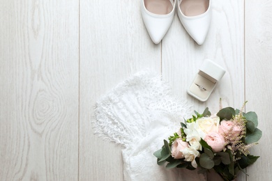 Flat lay composition with wedding high heel shoes on white wooden floor. Space for text