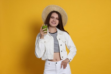 Beautiful young woman with glass of juice on yellow background