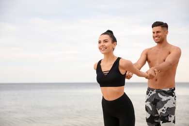 Couple doing exercise together on beach, space for text. Body training