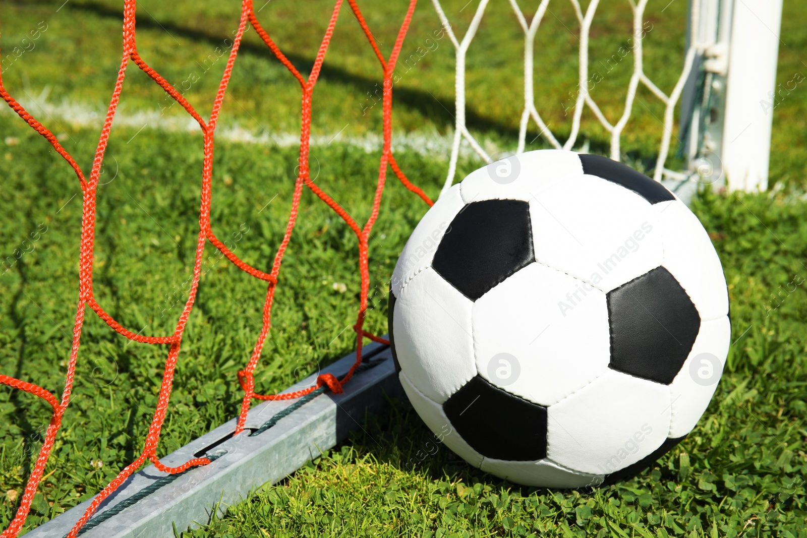 Photo of Soccer ball near net on green football field grass