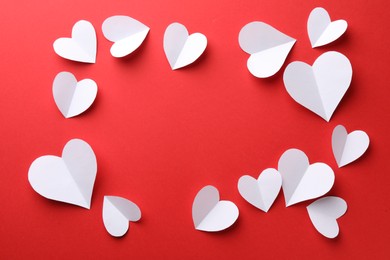 Photo of Frame of white paper hearts on red background, flat lay. Space for text