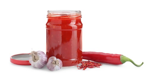 Photo of Spicy chili sauce in glass jar, garlic and pepper isolated on white