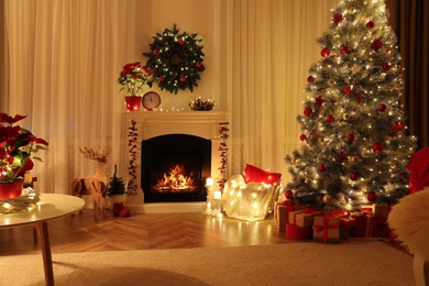 Photo of Beautiful living room interior with burning fireplace and Christmas tree in evening