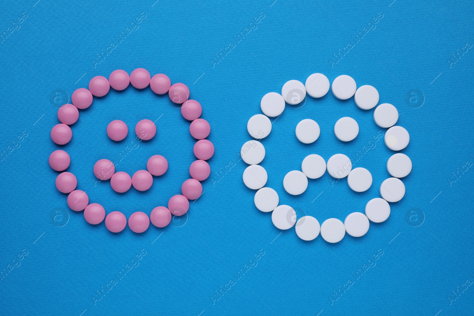 Photo of Sad and happy emoticons made of antidepressants on blue background, flat lay