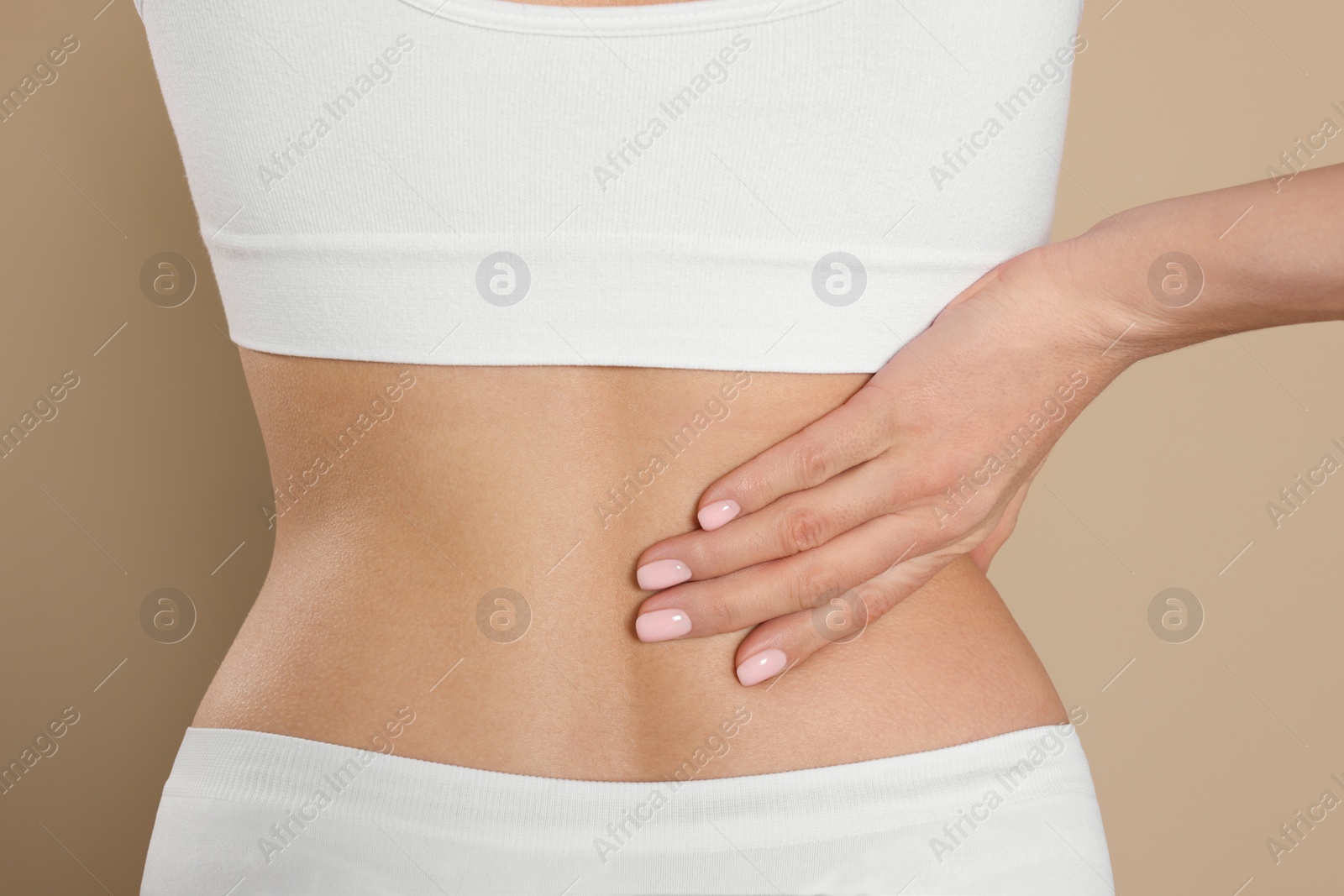 Photo of Woman suffering from pain in back on beige background, closeup