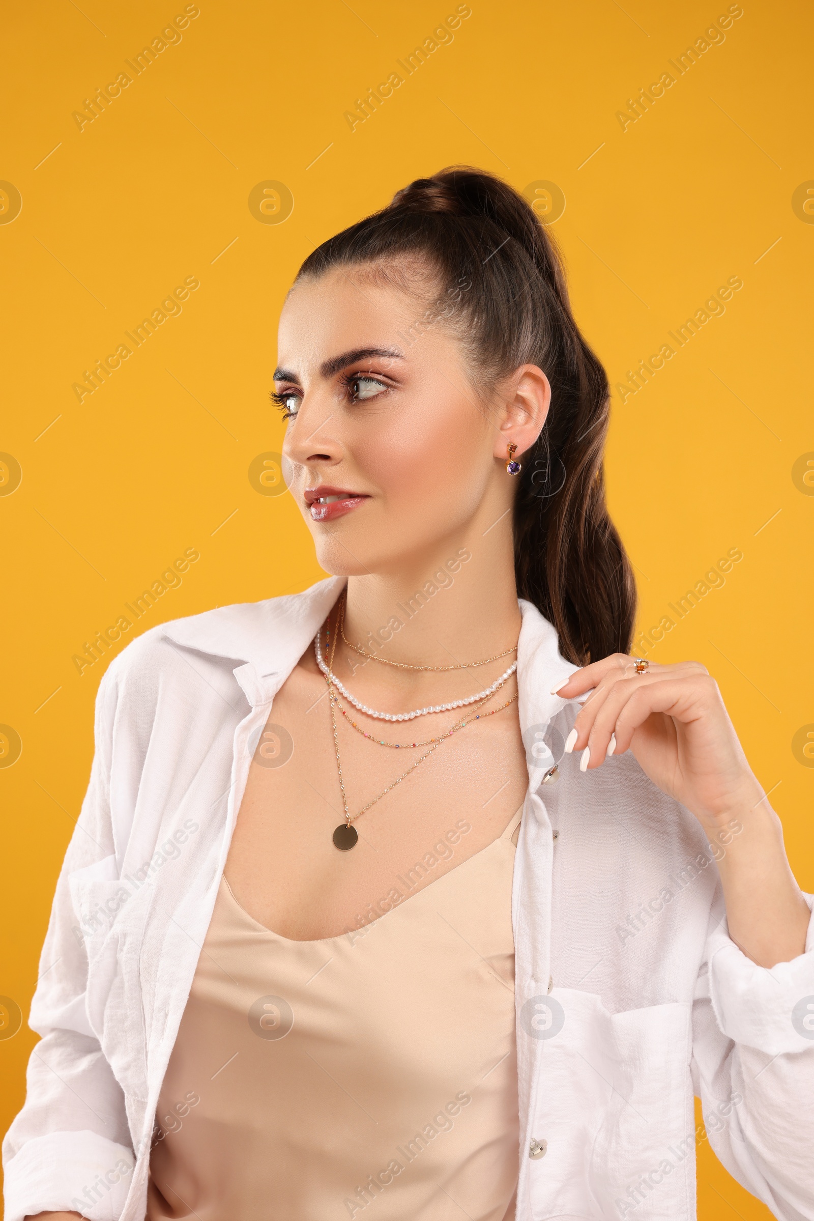 Photo of Beautiful woman with elegant jewelry on orange background