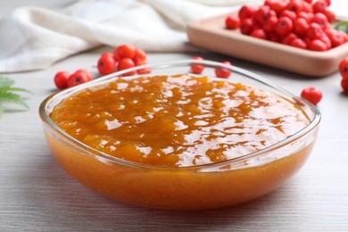 Photo of Delicious rowan jam in bowl on white wooden table, closeup