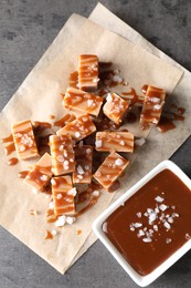 Photo of Tasty candies, caramel sauce and salt on grey table, top view