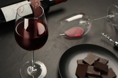 Tasty red wine and chocolate on black table