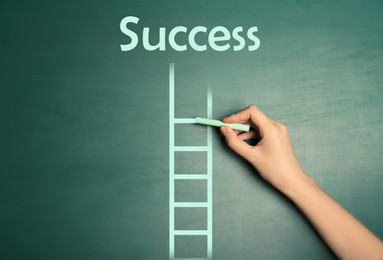 Image of Woman drawing ladder on green chalkboard, closeup. Steps to success