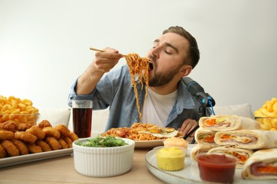 Food blogger eating in front of microphone at table against light background. Mukbang vlog