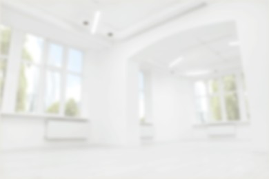 Image of Empty room with white walls and large windows, blurred view