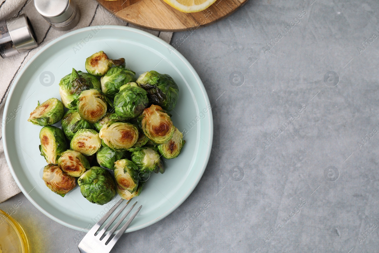 Photo of Delicious roasted Brussels sprouts served on grey table, top view. Space for text