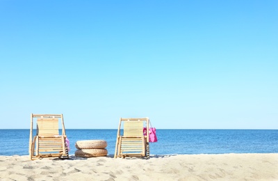 Photo of Empty wooden sunbeds and beach accessories on sandy shore