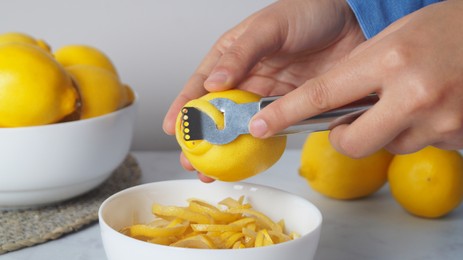 Woman zesting lemon at table, closeup view