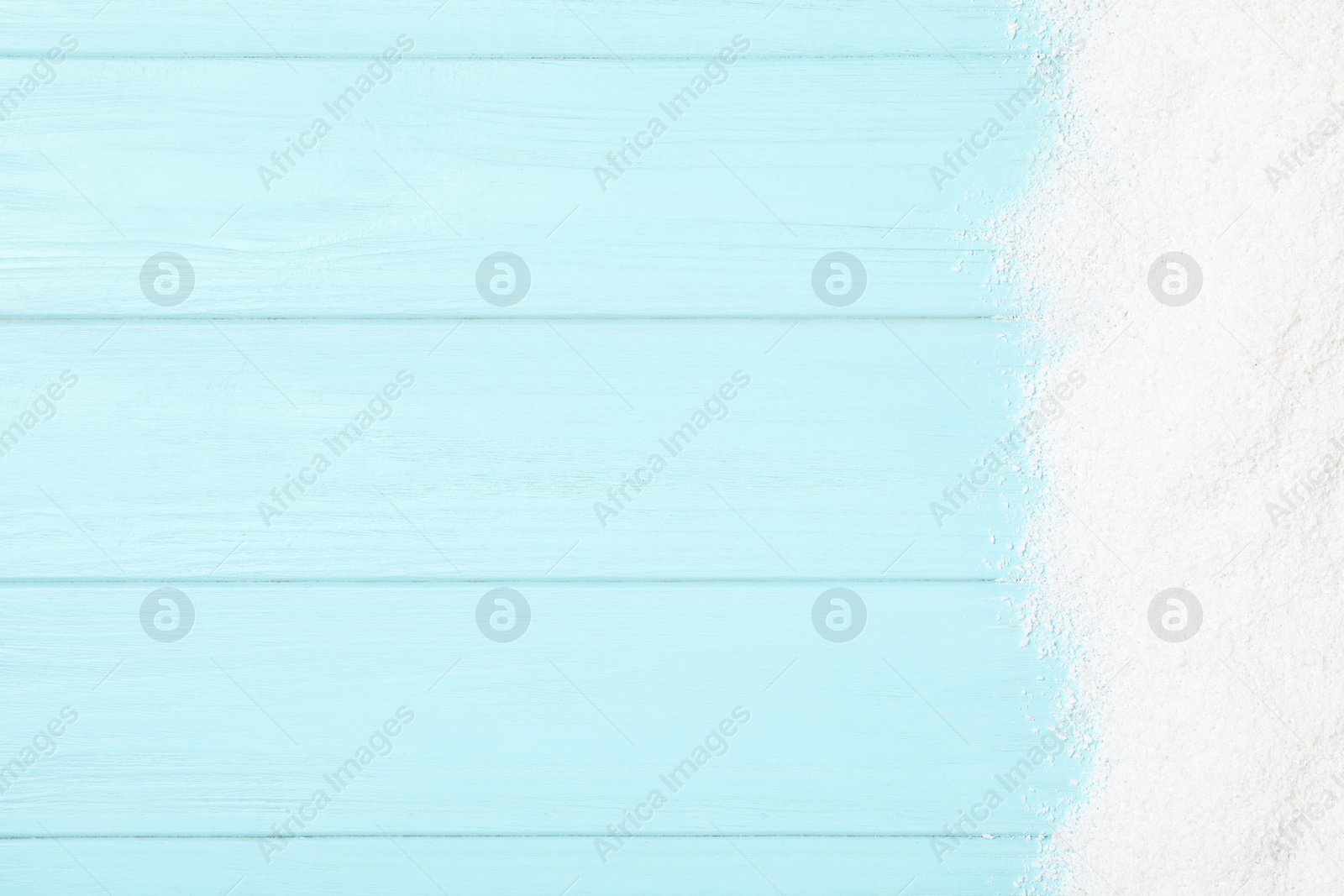 Photo of Artificial snow on light blue wooden background, top view with space for text. Christmas decor