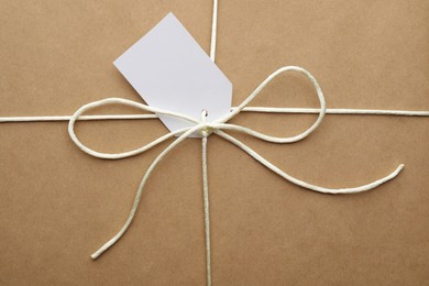 Parcel wrapped in kraft paper with tag as background, closeup