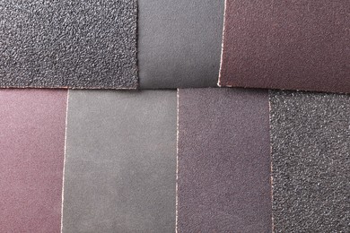 Photo of Many sheets of sandpaper as background, top view