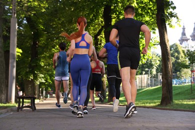 Photo of Group of people running in park, back view