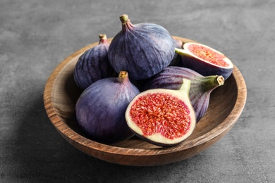 Bowl with fresh ripe figs on gray background. Tropical fruit