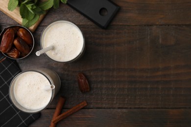 Glasses of delicious date smoothie and dried fruits on wooden table, flat lay. Space for text