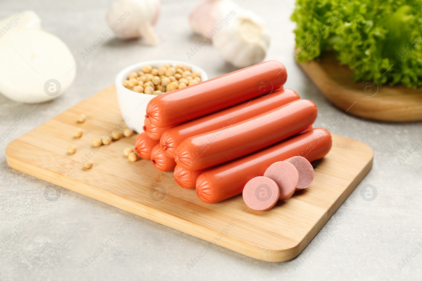Photo of Fresh raw vegetarian sausages and soybeans on grey table