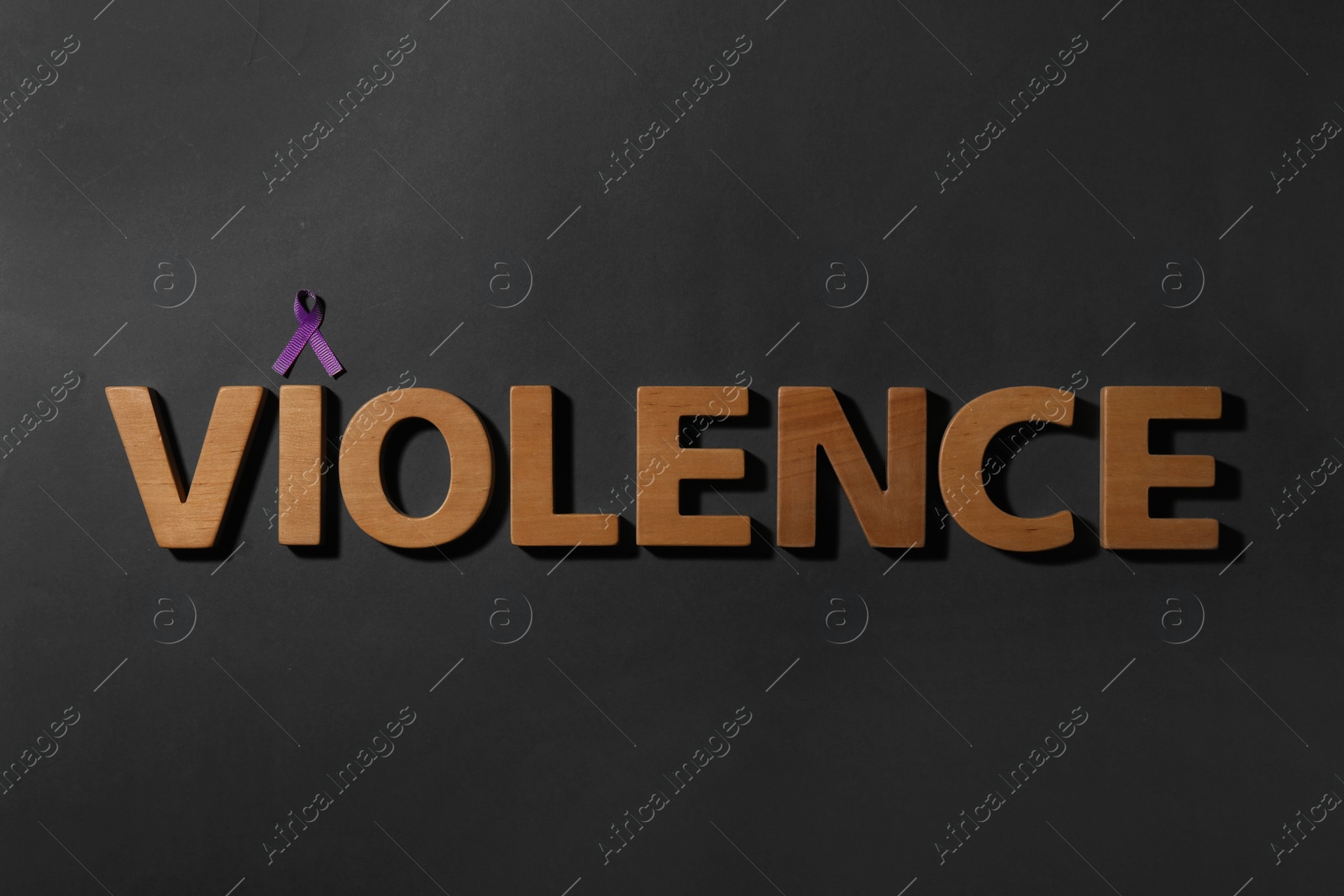 Photo of Purple awareness ribbon and word VIOLENCE made of wooden letters on black background, top view