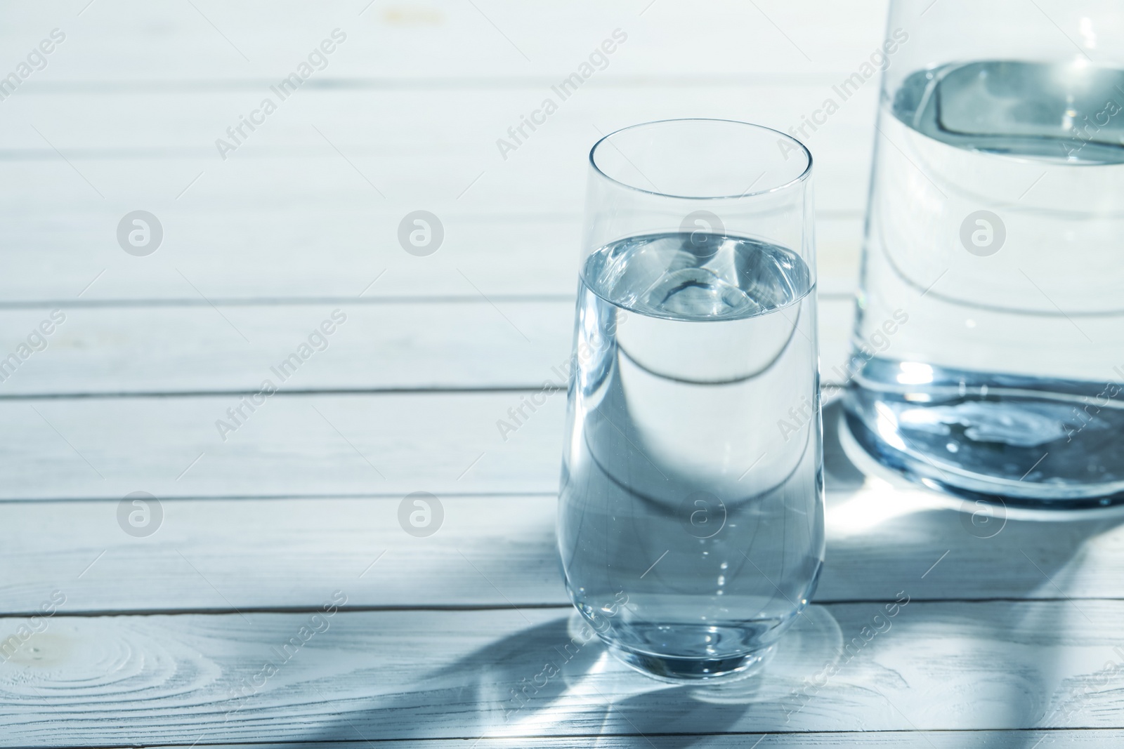 Photo of Jug and glass of water on grey wooden table, space for text. Refreshing drink