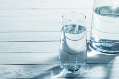 Jug and glass of water on grey wooden table, space for text. Refreshing drink