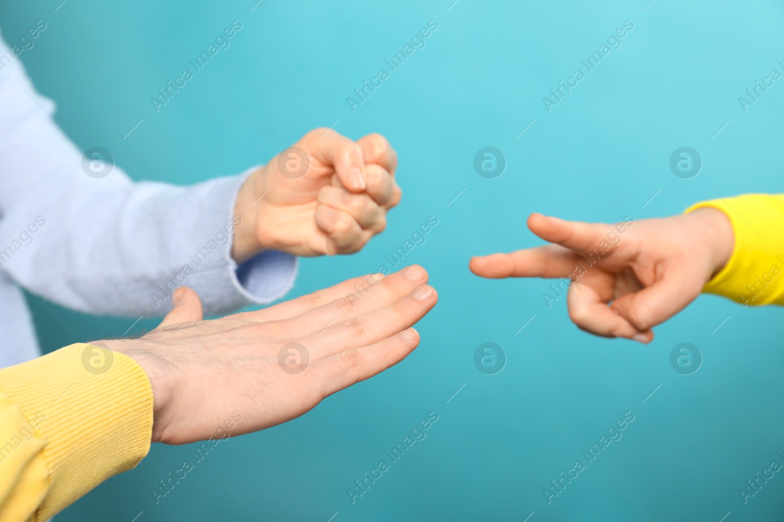 Photo of People playing rock, paper and scissors on light blue background, closeup