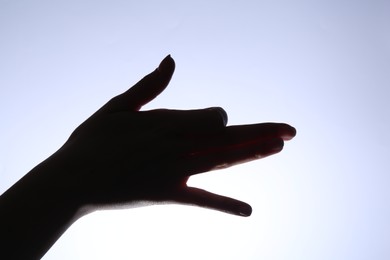 Photo of Shadow puppet. Woman making hand gesture like dog on light background, closeup