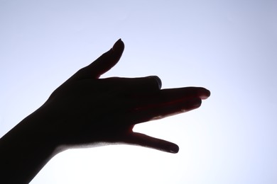 Shadow puppet. Woman making hand gesture like dog on light background, closeup