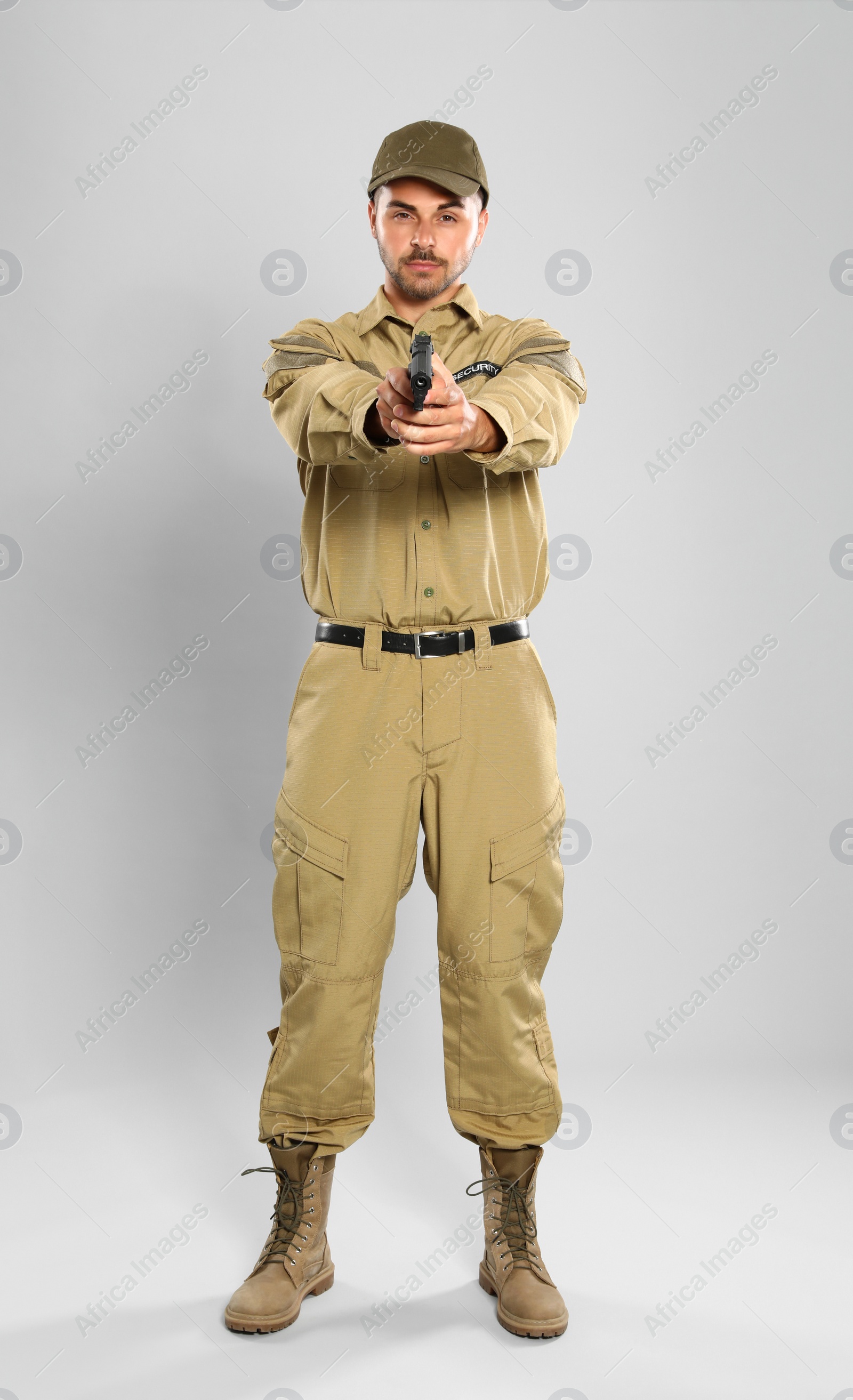 Photo of Male security guard in uniform with gun on grey background