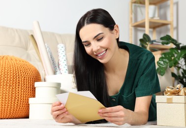 Happy woman reading greeting card on floor in living room