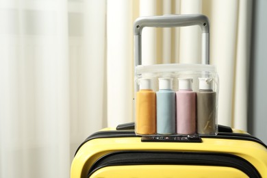 Photo of Cosmetic travel kit. Plastic bag with small containers of personal care products on suitcase indoors, space for text