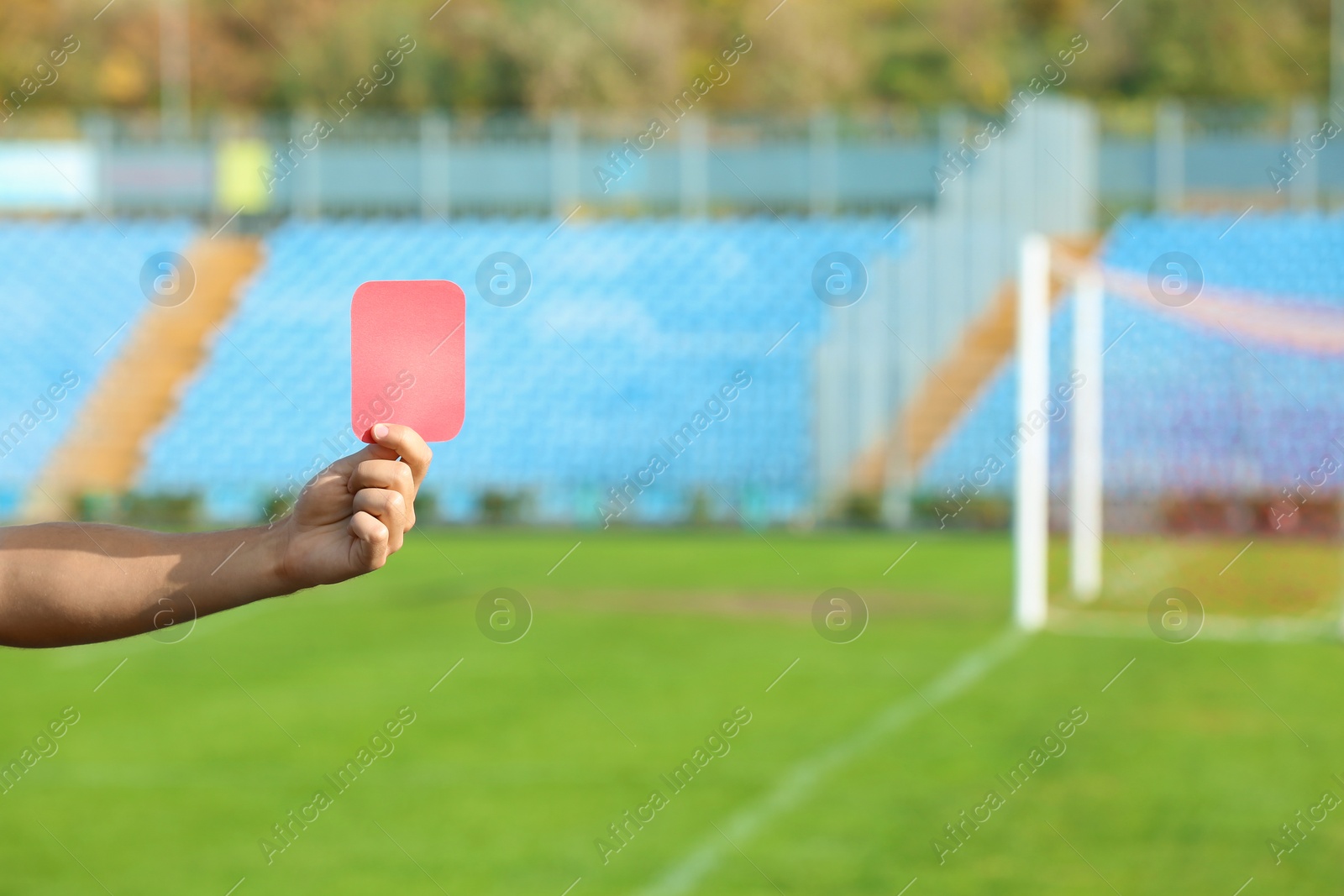 Photo of Football referee showing red card at stadium, closeup with space for text