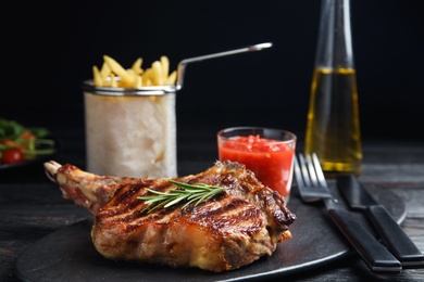 Photo of Tasty grilled beef steak on black wooden table