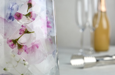 Glass vase with floral ice cubes on table, closeup. Space for text