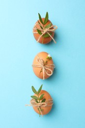 Chicken eggs and natural decor on light blue background, flat lay. Happy Easter