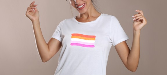 Image of Young woman wearing white t-shirt with lesbian flag on beige background, banner design. LGBT concept