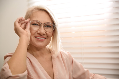 Photo of Beautiful mature woman in glasses at home. Space for text