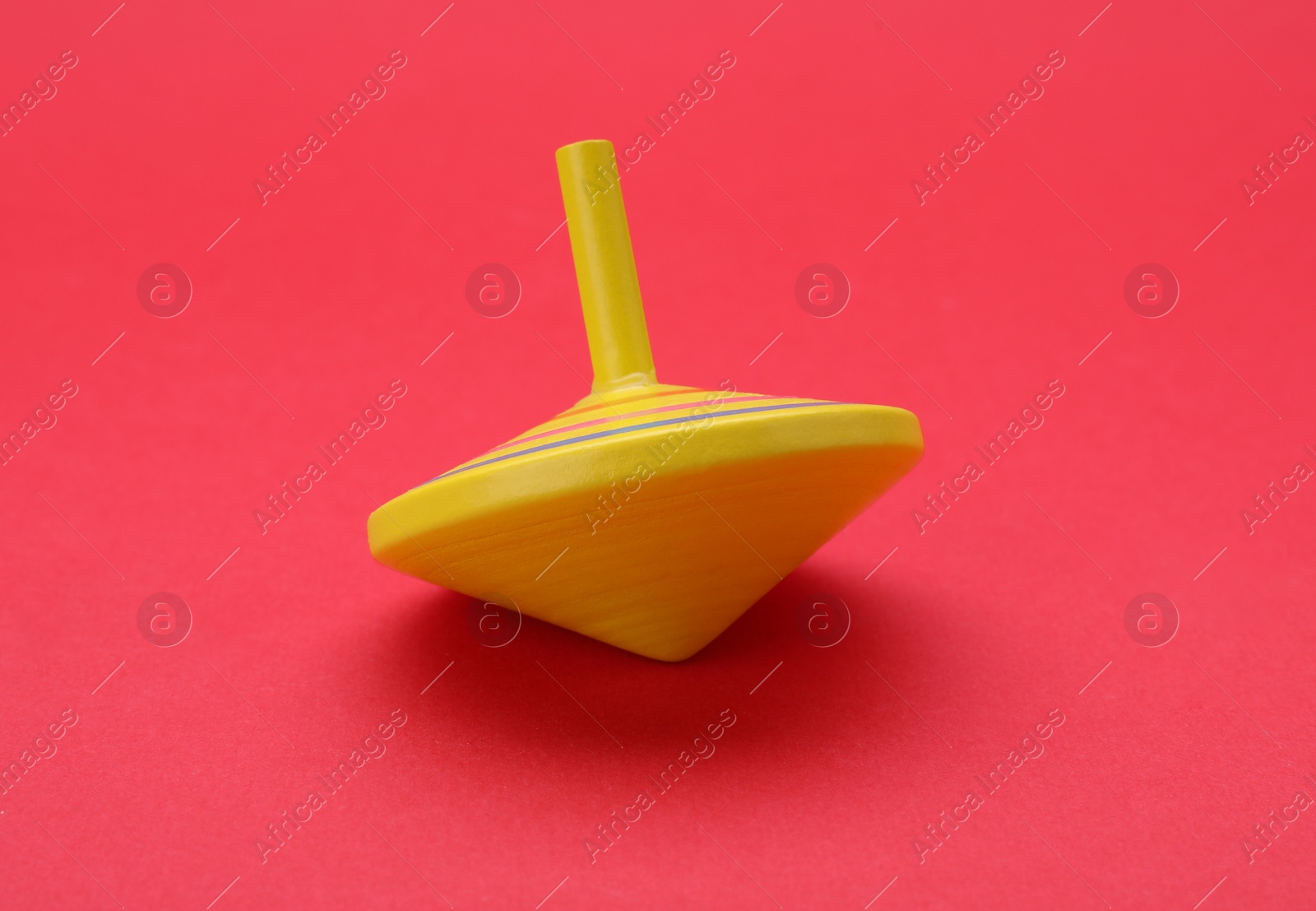 Photo of One bright spinning top on red background. Toy whirligig