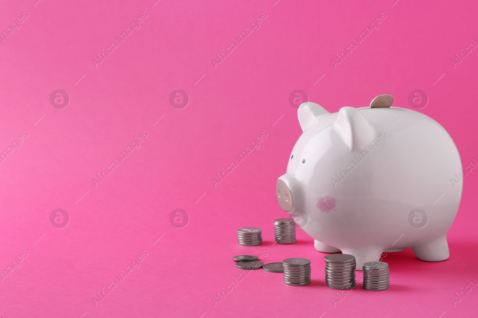 Photo of Financial savings. Piggy bank and coins on pink background, space for text