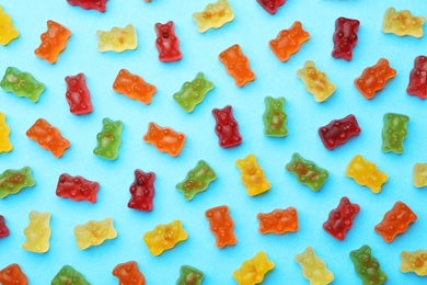 Photo of Delicious bright jelly bears on blue background, flat lay