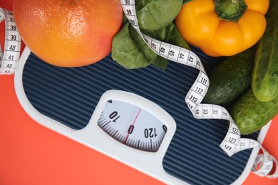 Photo of Scales, healthy food and measuring tape on orange background, top view