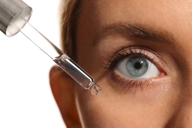 Woman applying cosmetic serum onto her face on white background, closeup