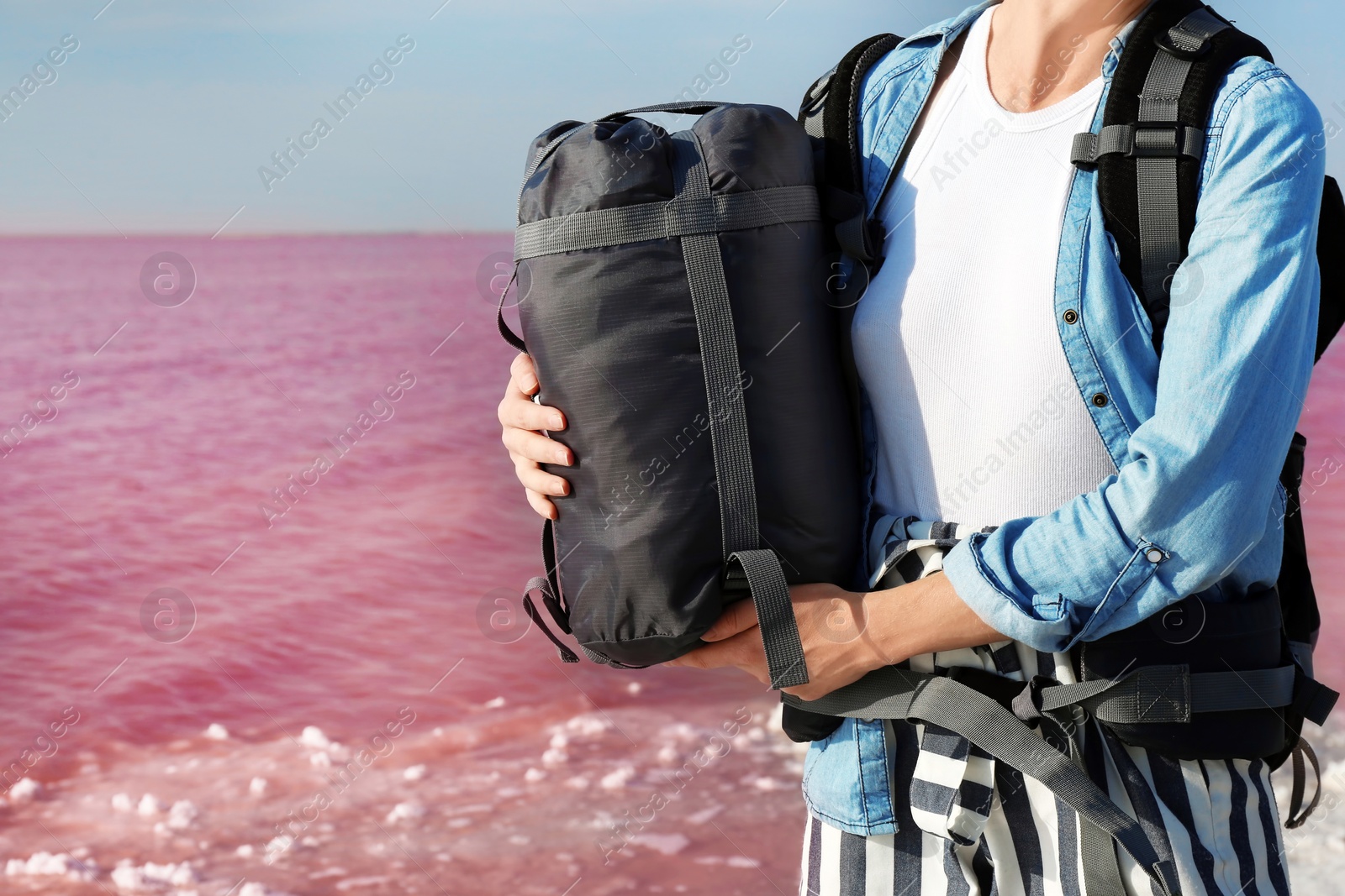 Photo of Woman with sleeping bag on coast of pink lake