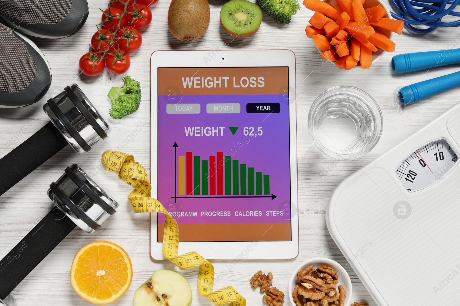 Photo of Tablet with weight loss calculator application, fitness items and different products on white wooden table, flat lay