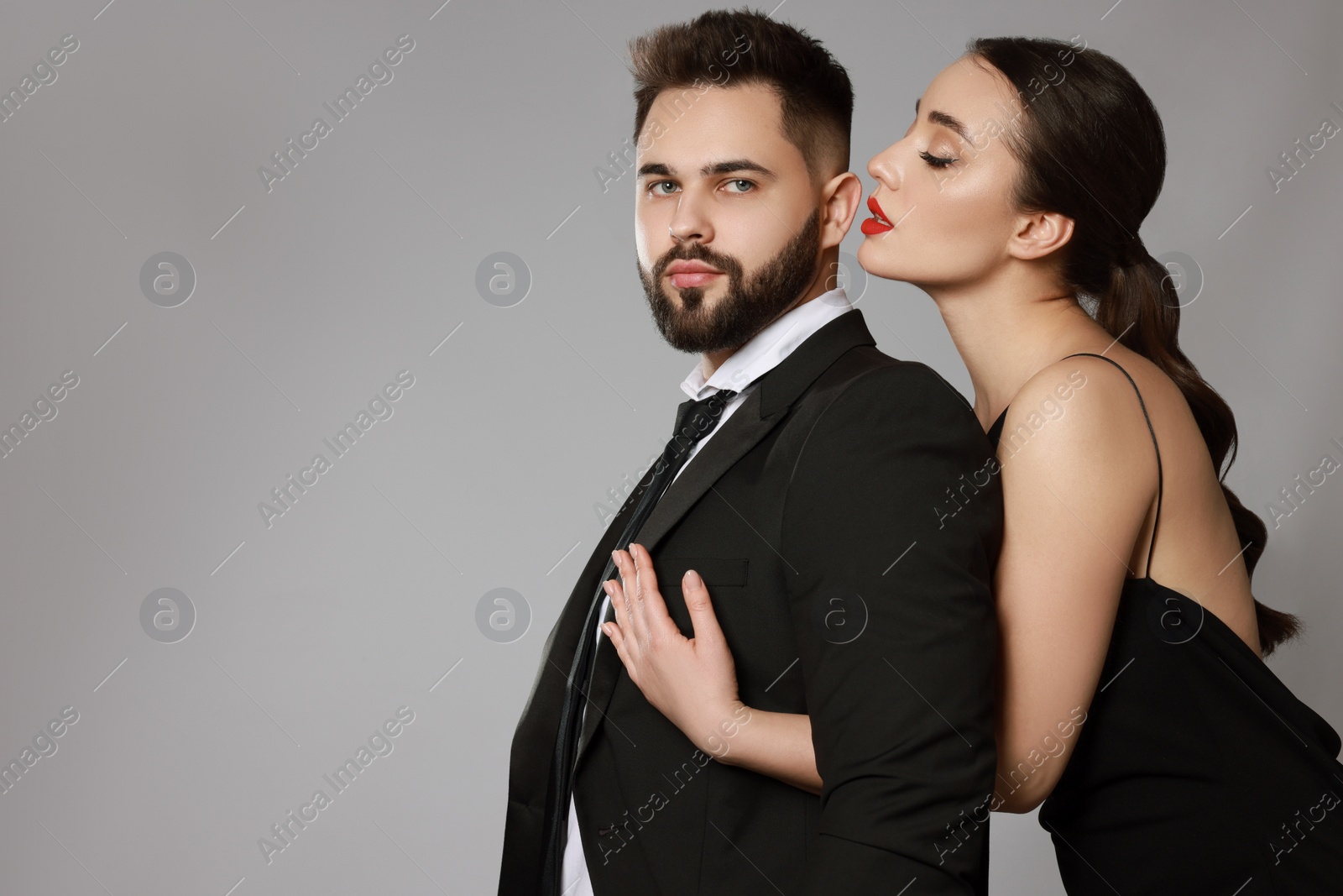 Photo of Handsome bearded man with sexy lady on grey background. Space for text