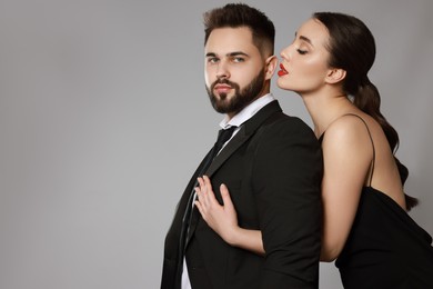 Photo of Handsome bearded man with sexy lady on grey background. Space for text